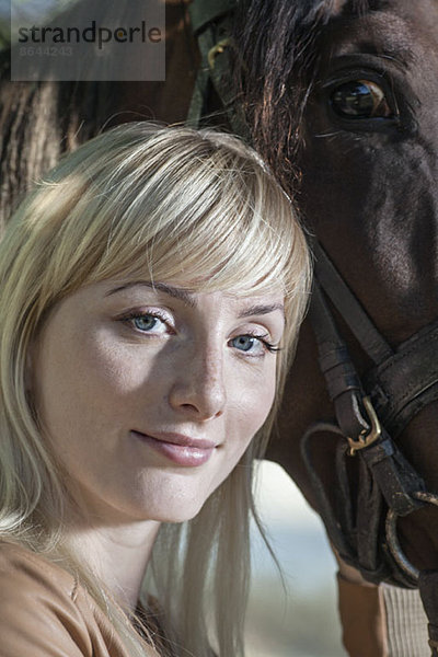 Porträt einer jungen Frau mit Pferd  lächelnd