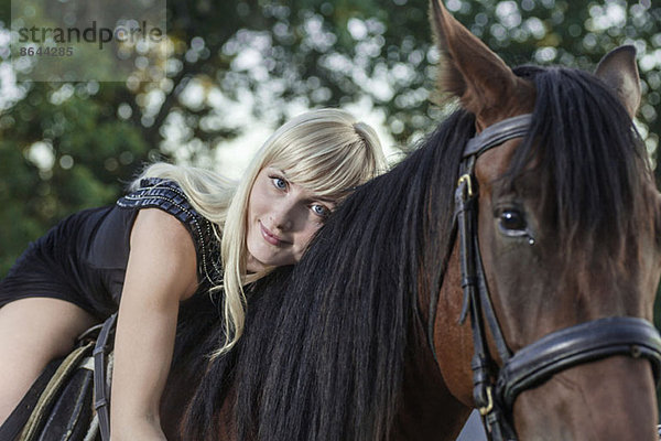 Junge Frau auf einem Pferd liegend