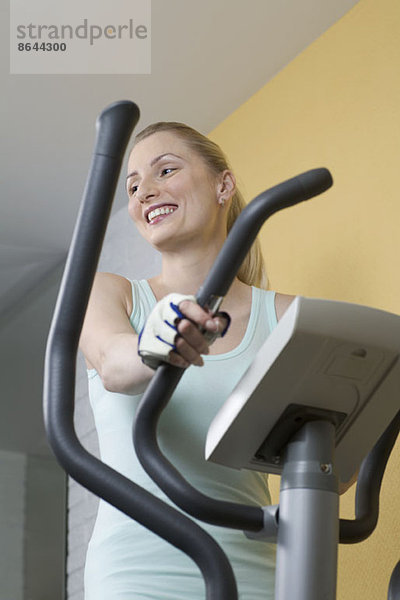 Junge Frau beim Training auf dem Heimtrainer