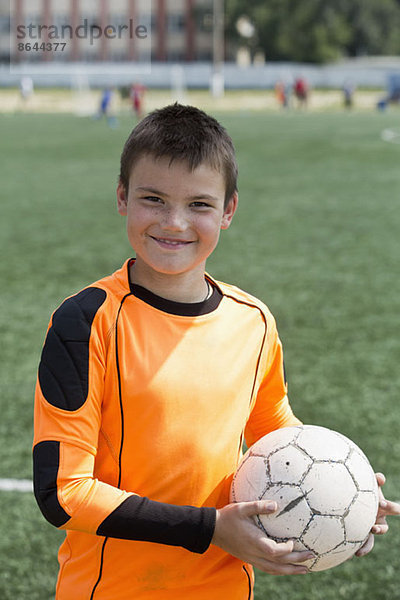 Porträt eines Jungen  der Fußball hält  lächelnd