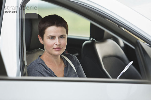 Porträt einer mittleren erwachsenen Frau im Auto sitzend