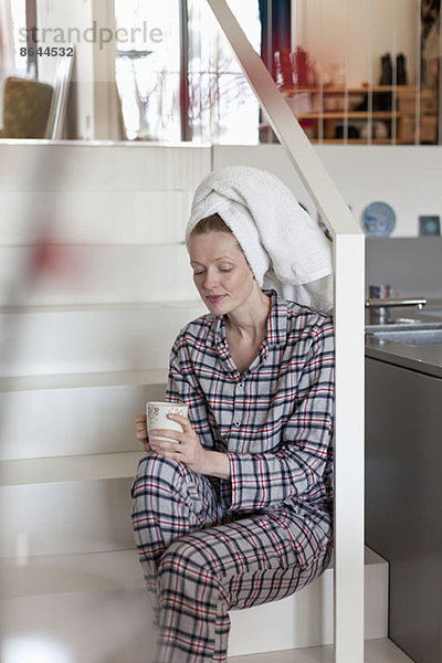 Frau mit Kaffeetasse auf der Treppe sitzend