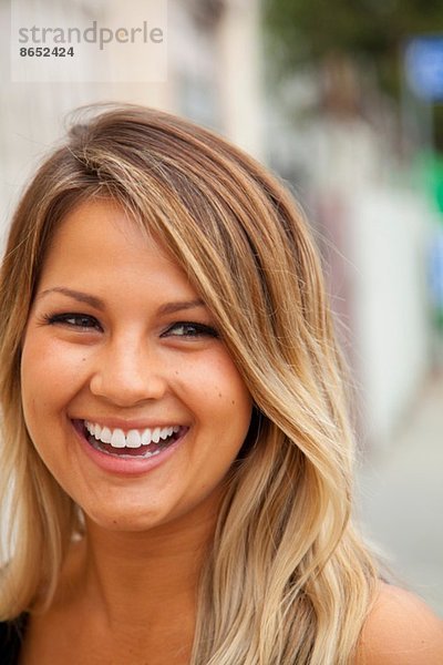 Porträt einer jungen Frau mit blonden Haaren  die lächelt