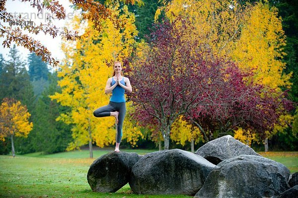 Junge Frau beim Yoga auf dem Felsen