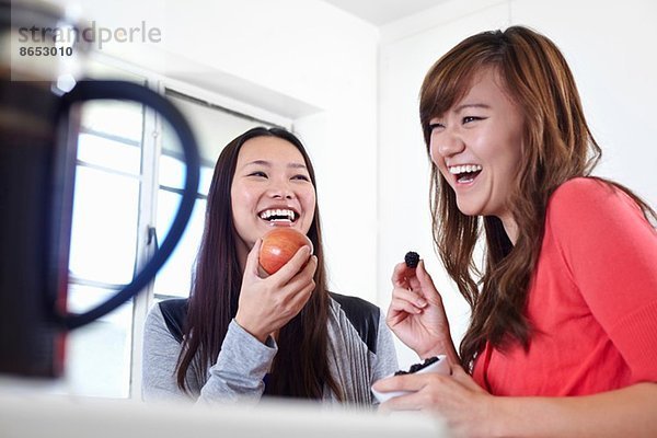 Zwei junge Frauen in der Küche beim Obstessen