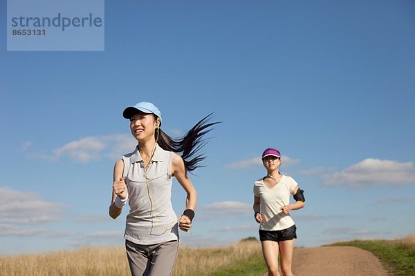 Zwei junge Frauen  die auf einem Feldweg laufen.