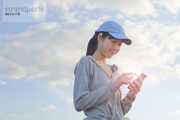 Junge Läuferin  die sich für Musik aus dem MP3-Player entscheidet