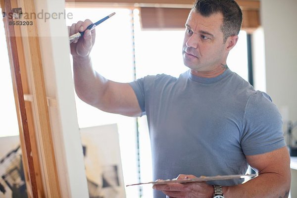 Reife Künstlerin auf Leinwand im Atelier