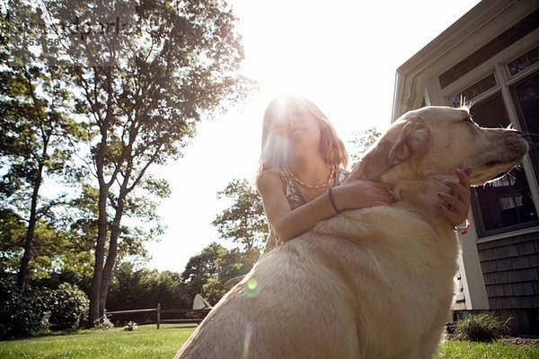 Junges Mädchen umarmt Haustier Labrador im Garten