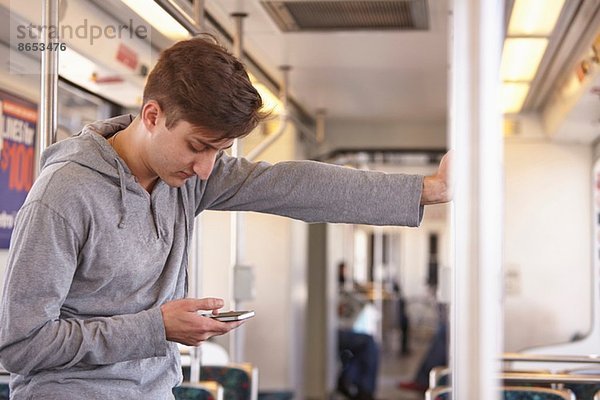 Mittlerer Erwachsener Mann mit Handy in der U-Bahn