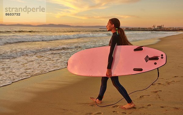 Mädchen am Strand mit rosa Surfbrett