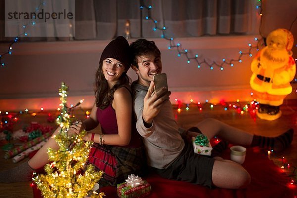 Junges Paar  das sich zu Weihnachten im Wohnzimmer niederlässt