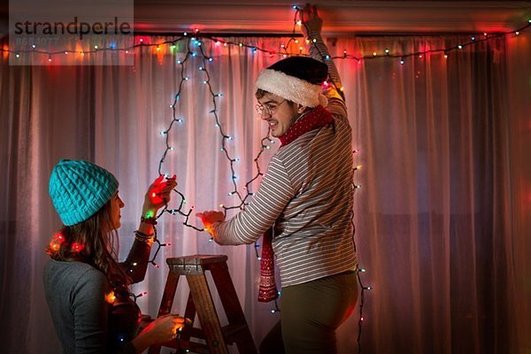 Junges Paar mit Lichterketten an Weihnachten