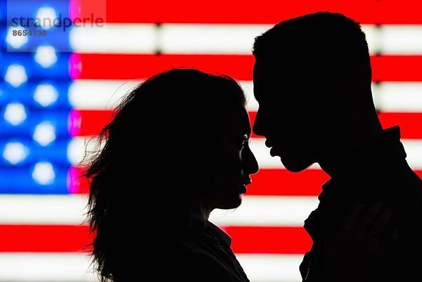 Silhouette eines jungen Paares vor amerikanischer Flagge