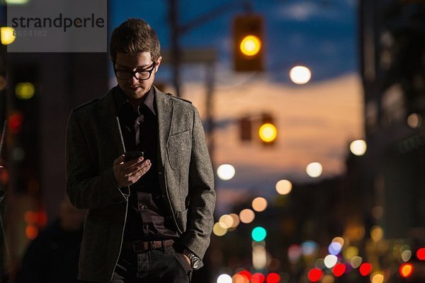 Junger Mann schlendert die Straße hinunter und schaut auf sein Handy  Toronto  Ontario  Kanada.