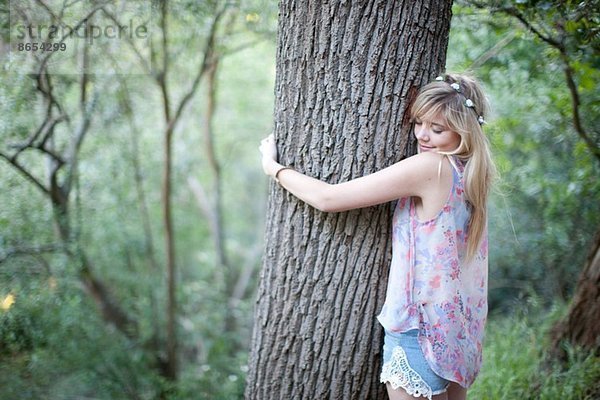 Teenagermädchen umarmt Baum im Wald