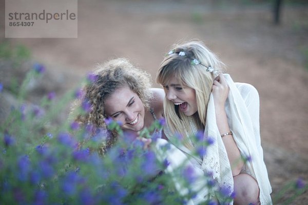 Zwei Teenager-Mädchen beim Betrachten von Wildblumen im Wald