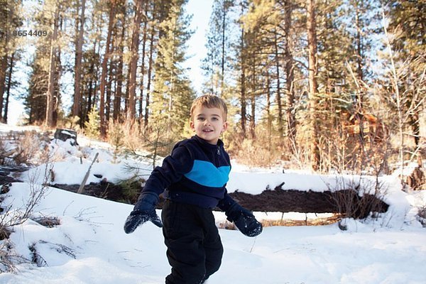 Männliches Kleinkind beim Spielen im verschneiten Wald