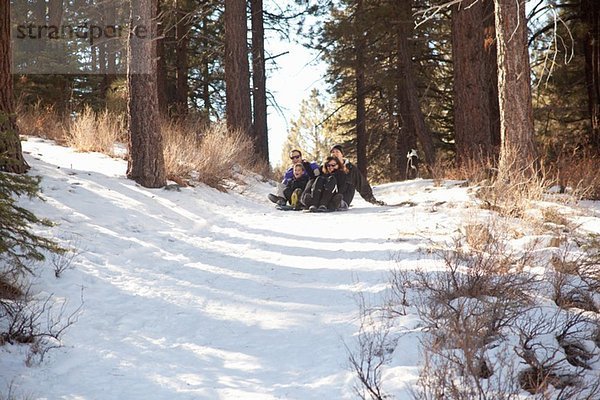 Junge und junge Erwachsene beim Rodeln im verschneiten Wald