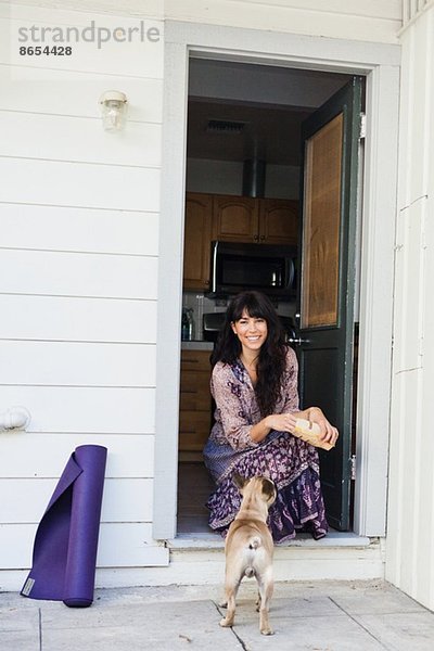 Junge Frau sitzend in der Tür mit Hund