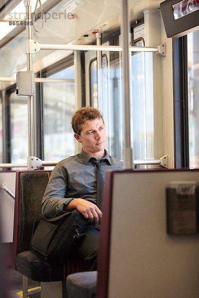 Mittlerer erwachsener Büroangestellter  der auf der Zugfahrt gelangweilt aussieht