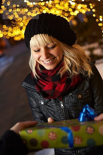 Junger Mann überreicht Weihnachtsgeschenk an Freundin auf der Stadtstraße