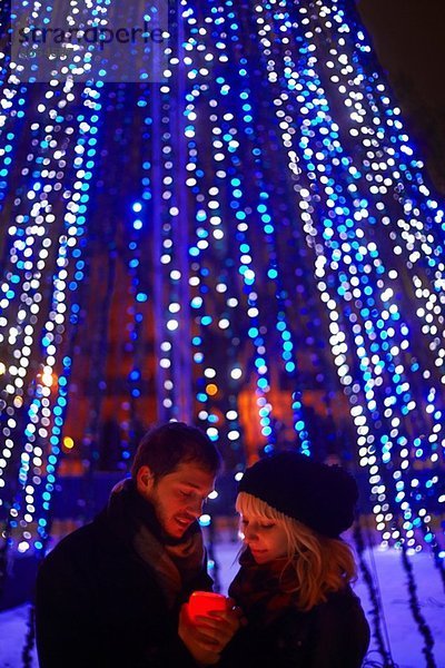 Junges Paar hält Kerze vor Stadt-Weihnachtslicht