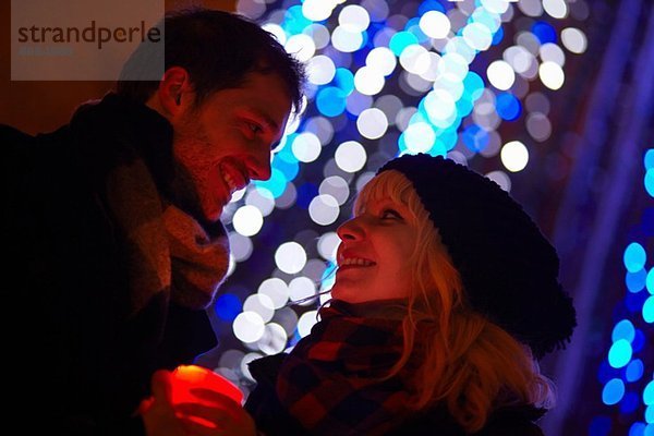 Junges Paar hält Kerze vor Stadt-Weihnachtslicht