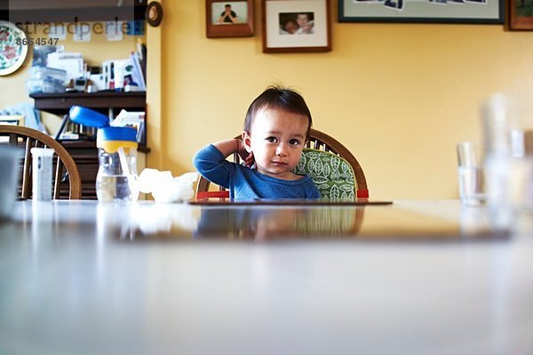 Kleiner Junge sitzt am Küchentisch