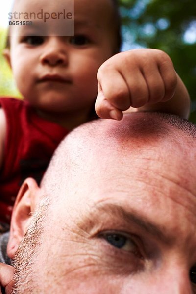 Nahaufnahme des Vaters  der den kleinen Sohn auf den Schultern trägt.