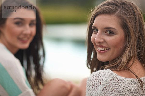 Zwei junge Frauen sitzen am Ufer des Flusses