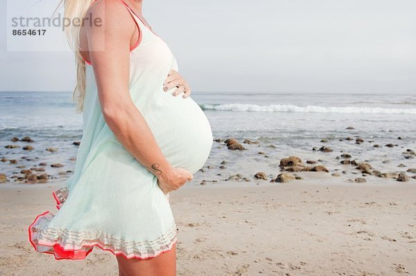 Geschnittenes Bild einer schwangeren jungen Frau am Strand