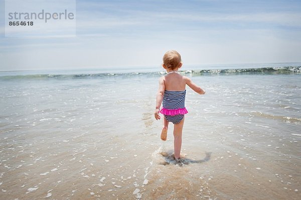 Weibliches Kleinkind  das ins Meer rennt.