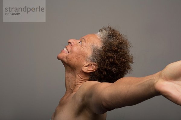 Studio-Porträt der nackten Seniorin mit ausgestreckten Armen