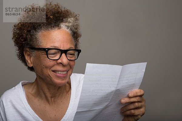 Studio-Porträt einer glücklichen Seniorin beim Lesen eines Briefes