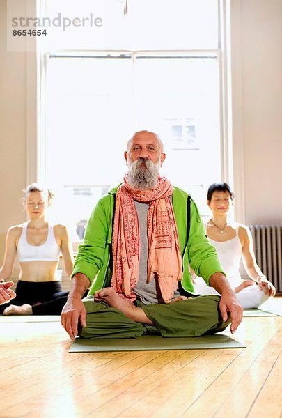 Reifer Mann in Lotus-Pose im Yoga-Kurs