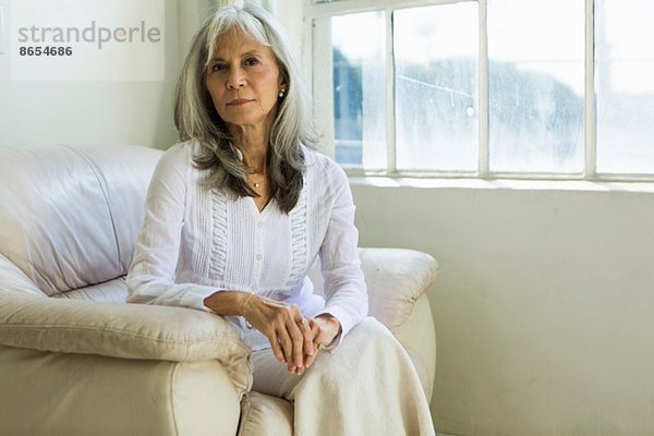 Porträt einer älteren Frau  die in der Wohnung sitzt
