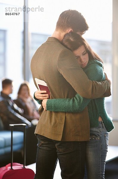 Junge Paare umarmen sich am Flughafen
