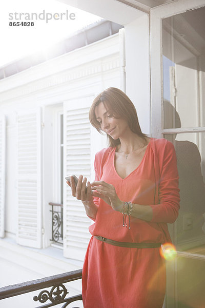 Frau auf dem Balkon mit Smartphone