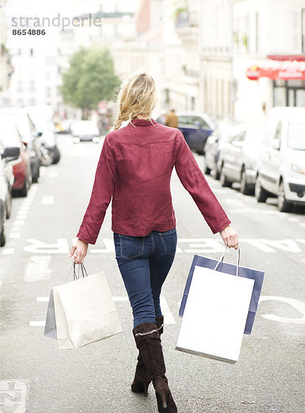Frau auf der Straße mit Einkaufstaschen  Rückansicht