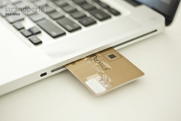 Kreditkarte  die aus der Seite des Laptops herausragt