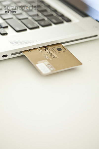 Kreditkarte  die aus der Seite des Laptops herausragt