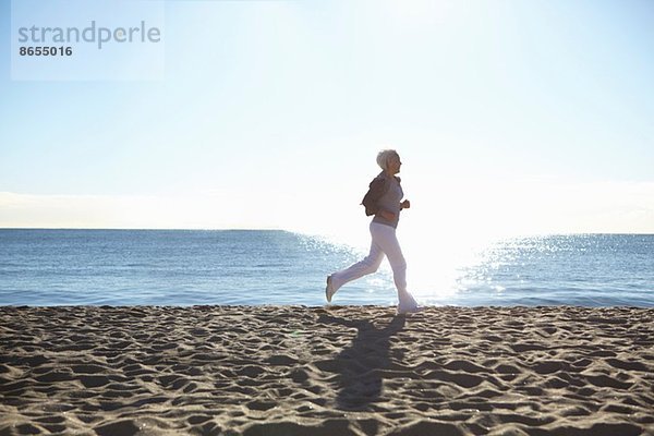Reife Frau beim Joggen am Strand