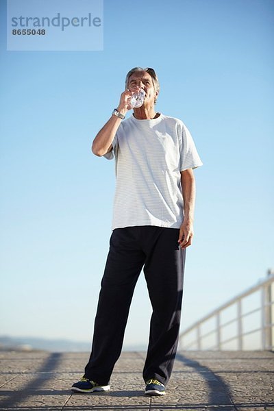 Senior Mann trinkt Wasser auf Spaziergang