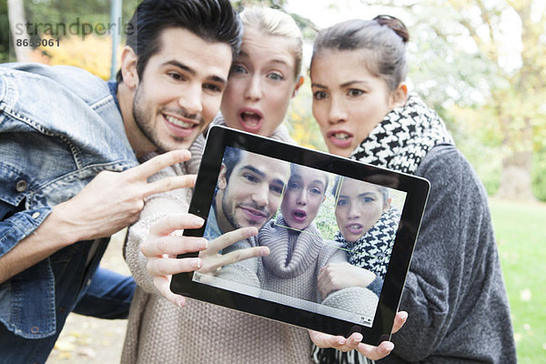 Freunde  die sich mit einem digitalen Tablett im Freien fotografieren.