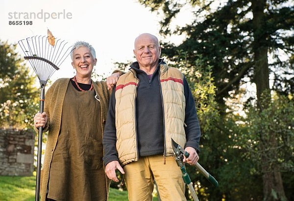 Seniorenpaar mit Rechen und Schere