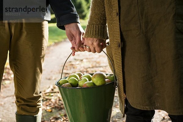 Paar tragende Eimer mit Äpfeln