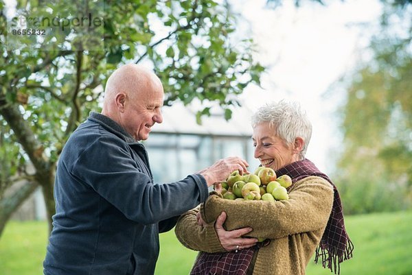 Porträt eines glücklichen Seniorenpaares mit Äpfeln