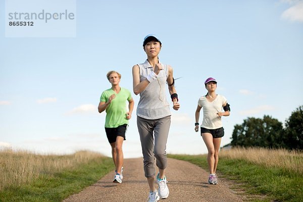 Drei junge Erwachsene joggen auf dem Feldweg