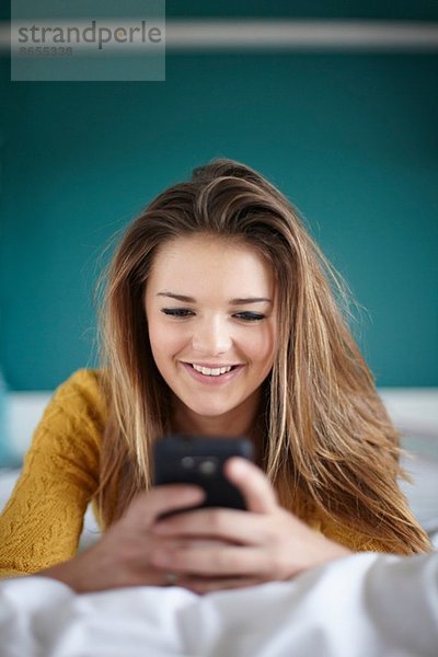 Teenager Mädchen im Schlafzimmer SMS auf Smartphone